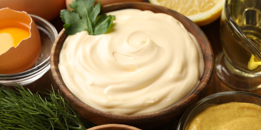 Wooden bowl of mayonnaise and ingredients for cooking Wooden bowl of mayonnaise and ingredients for cooking